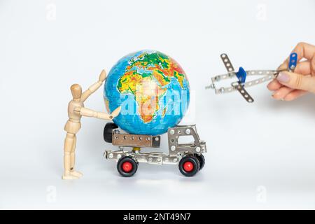 Globe sur une voiture de cargaison pour enfants et une personne en bois avec un dos et un petit avion dans ses mains sur blanc, le commerce international Banque D'Images