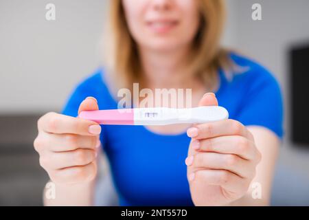 Blonde souriante tenue d'un test de grossesse positif. Banque D'Images