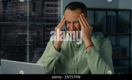 Malsain fatigué afro-américain homme se sentant mal de tête souffrant de migraine chronique épuisé homme d'affaires malade se sentent fatigue après le travail de bureau à Banque D'Images