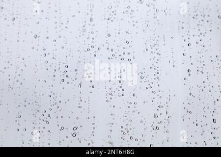 Gros plan sur les gouttes de pluie sur la fenêtre pendant la mousson. Banque D'Images