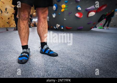 Homme grimpant portant des chaussures murales intérieures sur ses pieds, debout sur un tapis de sécurité doux. Banque D'Images
