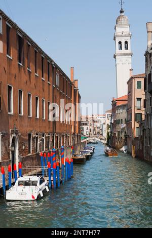 Bateaux amarrés et bateau-taxi sur un canal étroit et de vieux bâtiments résidentiels, clocher de l'église penchée, San Marco, Venise, Italie. Banque D'Images