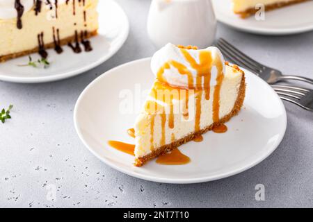 Tranche d'un cheesecake New-yorkais traditionnel à la crème fouettée à la dolope et à la sauce caramel Banque D'Images