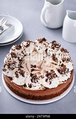 Cheesecake au chocolat sur un support à gâteau avec crème fouettée et boucles au chocolat Banque D'Images