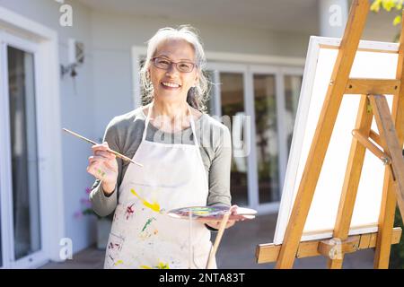 Portrait d'une femme asiatique âgée heureuse peint sur un chevalet dans le jardin Banque D'Images
