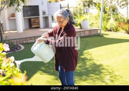 Bonne femme asiatique senior jardinage, arrosage de plantes Banque D'Images