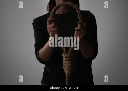 Femme tenant le nœud de corde sur fond clair, gros plan Banque D'Images