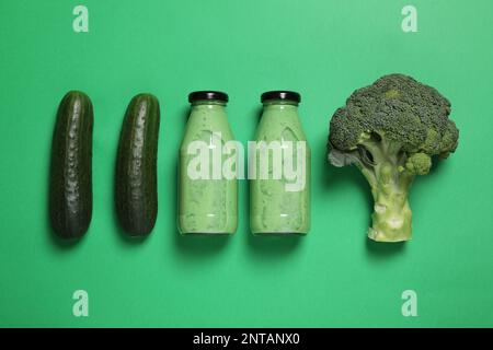 Bouteilles de délicieux smoothie et ingrédients sur fond vert, plat Banque D'Images