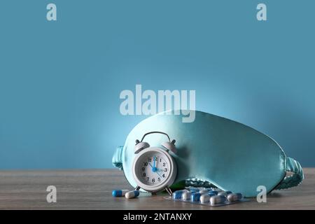 Masque de couchage, réveil et pilules sur table en bois. Traitement de l'insomnie Banque D'Images