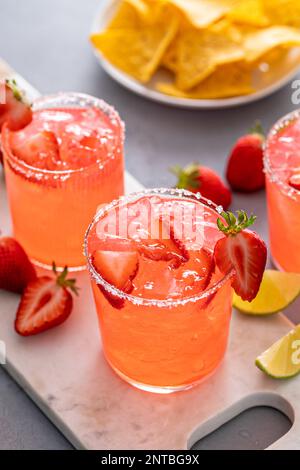 Cocktail de margarita aux fraises avec citron vert et glace pilée servi avec des chips de tortilla Banque D'Images