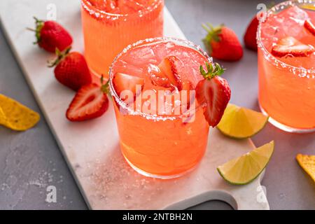 Cocktail de margarita aux fraises avec citron vert et glace pilée servi avec des chips de tortilla Banque D'Images