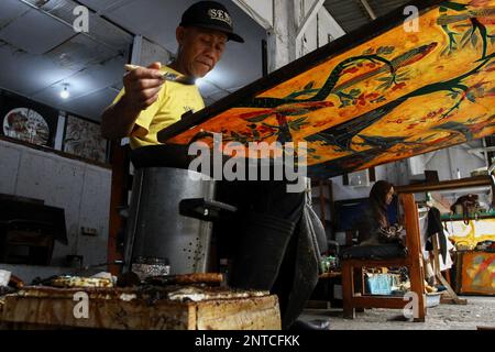 Yogyakarta, Indonésie. 27th févr. 2023. Un artisan travaille sur un batik dessiné à la main pour une décoration murale à la galerie Batik Seno, Yogyakarta. Les batiks décoratifs se vendent pour quelque chose entre 150 000 à 3 millions de roupies indonésiennes (environ US$ 10-200) selon la taille et la qualité. La galerie propose également des forfaits d'apprentissage batik pour les touristes étrangers. (Photo par Angga Budhiyanto/SOPA Images/Sipa USA) crédit: SIPA USA/Alay Live News Banque D'Images