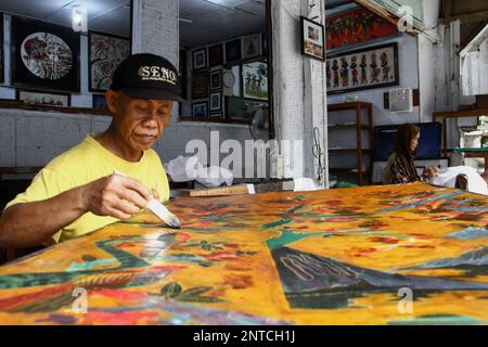 Yogyakarta, Indonésie. 27th févr. 2023. Un artisan travaille sur un batik dessiné à la main pour une décoration murale à la galerie Batik Seno, Yogyakarta. Les batiks décoratifs se vendent pour quelque chose entre 150 000 à 3 millions de roupies indonésiennes (environ US$ 10-200) selon la taille et la qualité. La galerie propose également des forfaits d'apprentissage batik pour les touristes étrangers. (Photo par Angga Budhiyanto/SOPA Images/Sipa USA) crédit: SIPA USA/Alay Live News Banque D'Images