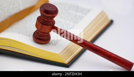 Livre avec des bords de page dorée et un signet de ruban usé placé avec un gavel de bois poli sur fond blanc montre la justice et la loi instruite dans l'Union Banque D'Images