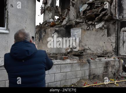Borodyanka, Ukraine. 26th févr. 2023. Un homme prend des photos du travail de Banksy avec son téléphone, le travail de l'artiste anglais Banksy est visible sur le mur détruit, après que la Fédération de Russie a attaqué la ville de Borodyanka, les autorités ont décidé de sauver le travail de Banksy et maintenant ils sont protégés par le système. Crédit : SOPA Images Limited/Alamy Live News Banque D'Images