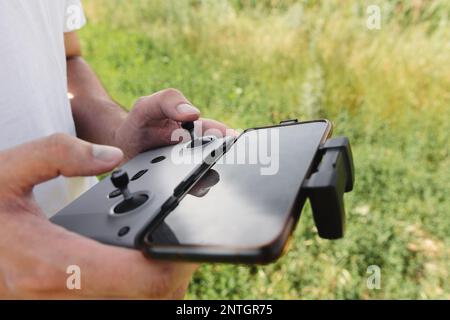 Panneau de commande avec un smartphone dans les mains d'un pilote de drone en extérieur Banque D'Images