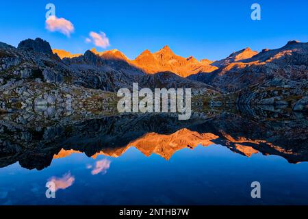 CIMA Laghetto et Cima di Cornisello, illuminés par les premiers rayons du soleil de la journée, reflétés dans le lac Lago Nero au lever du soleil. Banque D'Images