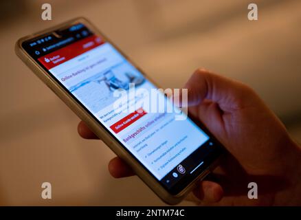 Berlin, Allemagne. 27th févr. 2023. Un homme tient un smartphone avec une page de banque en ligne ouverte. Credit: Monika Skolimowska/dpa/Alay Live News Banque D'Images