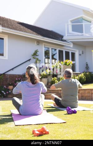 Heureux senior divers couple faisant du yoga et méditant dans le jardin Banque D'Images