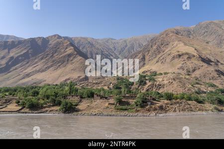 Paysage panoramique avec village de montagne traditionnel sur le côté afghan de la vallée de la rivière Panj, vu du district de Darvaz, Gorno-Badakshan, Tadjikistan Pamir Banque D'Images