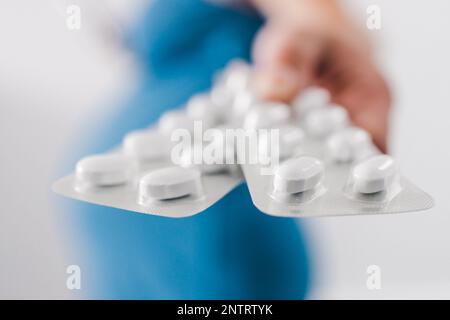 femme enceinte tenant des comprimés de multivitamines dans sa main et montrant sa bosse au dernier stade de la grossesse Banque D'Images