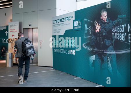 Nuremberg, Allemagne. 28th févr. 2023. Un visiteur d'un salon passe devant un présentoir du centre d'assistance technique. Le salon des technologies de sécurité pour les membres des agences de sécurité et des forces armées a déjà rapporté un record de 377 exposants de 36 pays l'année dernière. Credit: Daniel Vogl/dpa/Alay Live News Banque D'Images