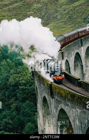 Train à vapeur Jacobite passant au-dessus du viaduc de Glenfinnan rendu célèbre par les films de Harry Potter. Situé dans la vallée avec des montagnes en Ecosse Banque D'Images