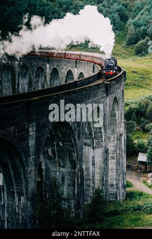 Train à vapeur Jacobite passant au-dessus du viaduc de Glenfinnan rendu célèbre par les films de Harry Potter. Situé dans la vallée avec des montagnes en Ecosse Banque D'Images