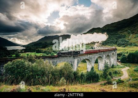 Train à vapeur Jacobite passant au-dessus du viaduc de Glenfinnan rendu célèbre par les films de Harry Potter. Situé dans la vallée avec des montagnes en Ecosse Banque D'Images