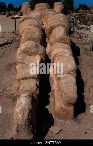 L'Atlas disparu se trouve devant sa némèse, Zeus: réplique pleine grandeur de 8M de long de l'un des 38 piliers colossaux de télamon qui autrefois ont soutenu les parties supérieures du vaste temple de Zeus olympique dans la vallée des temples, le site de l'Akragas grec antique à Agrigento, Sicile, Italie. Le temple en ruines, fondé en 480 av. J.-C., est l'une des plus grandes structures doriques du monde. Banque D'Images