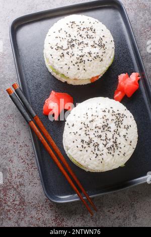 Hamburger au saumon à sushis maison avec avocat, sésame noir et gingembre sur une assiette sur la table. Vue verticale du dessus Banque D'Images