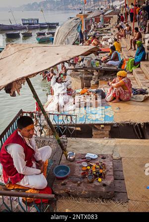 Un Pandits (saint homme et prêtre qui effectue des cérémonies) attendent les clients, sur les ghats du Gange, Varanasi, Uttar Pradesh, Inde. Banque D'Images