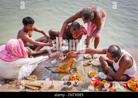 Les pèlerins faisant une offrande rituelle et la prière, ghats du Gange, Varanasi, Uttar Pradesh, Inde. Banque D'Images