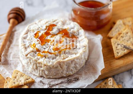 camembert, fromage français doux, servi avec du miel liquide et des craquelins, vue du dessus Banque D'Images
