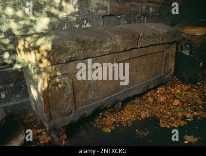 Un cercueil en pierre romaine sculpté (sarcophage) dans une arcade à côté de l'entrée de la rue du musée York Museum Gardens, North Yorkshire, Angleterre, Royaume-Uni. Banque D'Images