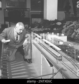 Modèle de train en 1950s. Un homme regarde quand le train modèle le passe sur son chemin sur le paysage sur une table en face de lui. À ce moment-là un passe-temps commun bien que cette photo soit probablement prise dans un musée ou une exposition. Suède 1953 Kristoffersson réf. BM25-6 Banque D'Images