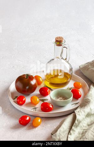 plateau rond avec différentes variétés de tomates, servi avec du sel et de l'huile d'olive, vue latérale, espace copie Banque D'Images