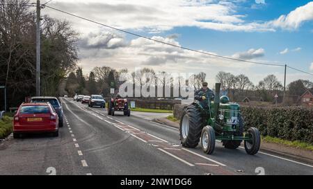 Un passionné conduit son tracteur d'époque Field Marshall et est suivi par un autre tracteur d'époque et une gamme de voitures à Wisborough Green, Royaume-Uni. Banque D'Images