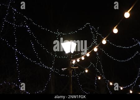 Lampadaire vintage la nuit entourée de cordes de lumières d'arbre Banque D'Images