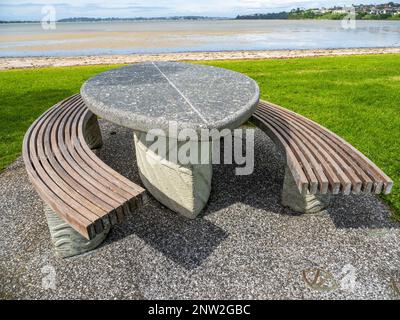 Cette image montre une table en pierre avec deux bancs à côté sur l'herbe Banque D'Images