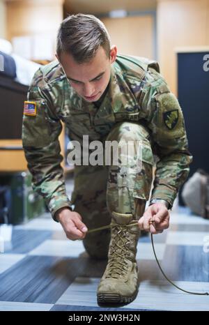 Brave est l'homme qui porte des bottes de combat. Coup de jeune soldat portant ses lacets de bottes dans les dortoirs d'une académie militaire. Banque D'Images