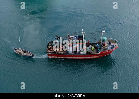 Vue aérienne d'un bateau de pêche commercial qui tracte un skiff hors-bord au départ du port de Porto Grande dans les îles du Cap-Vert. Image colorée. Banque D'Images