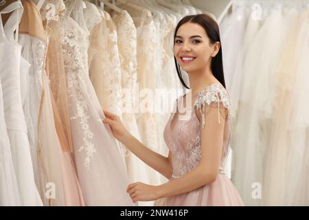 Jeune femme choisissant la robe de mariage dans le salon Banque D'Images