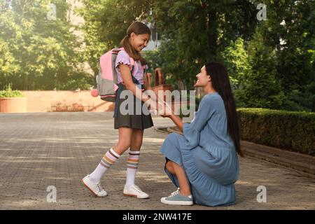 Mère qui dit au revoir à sa fille avant l'école à l'extérieur Banque D'Images