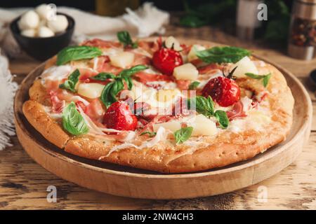 Pizza pita avec prosciutto, ananas, tomates grillées et œuf sur table en bois, en gros plan Banque D'Images