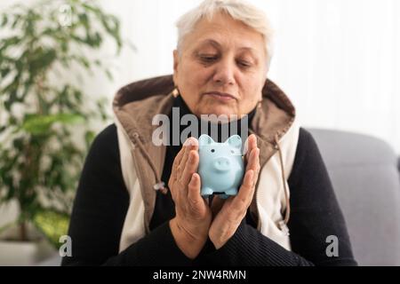 Gros plan d'une femme âgée tenant une caisse d'argent de porc. Femme âgée mains tenant une porcgybank. Concept d'économie d'argent pour les personnes âgées. Banque D'Images