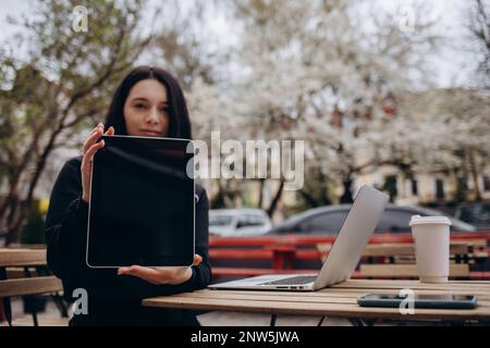 Image de maquette d'une femme d'affaires tenant un Tablet pc noir avec écran blanc vierge dans le bureau Banque D'Images