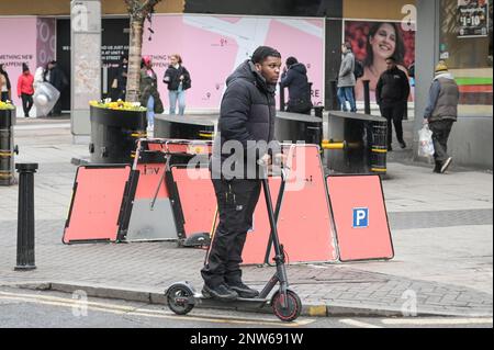 Birmingham, le 28th février 2023 - Un homme conduit illégalement son scooter électrique personnel après un vide VOI électrique location de scooter rack dans le centre de Birmingham - VOI scooters, la seule compagnie de location de scooter disponible à Birmingham va fermer leurs opérations le mardi 28th février à 11pm. Les scooters électriques étaient déjà minces sur le sol dans la deuxième ville d'Angleterre après que la compagnie a déclaré qu'ils allaient enlever les véhicules au cours des prochaines semaines. L'entreprise a loué des scooters pour une période d'essai, mais a décidé de ne pas poursuivre le contrat et aucune autre entreprise n'a pas fait le pas Banque D'Images