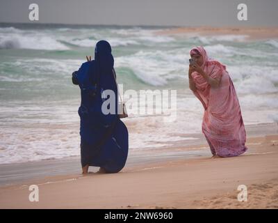 Une femme prend une photo d'une autre femme avec son smartphone. C'est à Bahamas Beach, Nouakchott, Mauritanie Banque D'Images