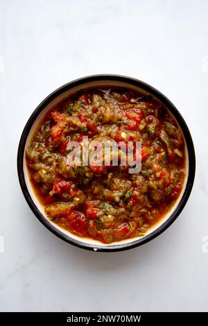 Meze d'aubergines grecques dans un bol en céramique avec une cuillère. Aubergines cuites au four avec tomates et poivrons avec ail. Banque D'Images